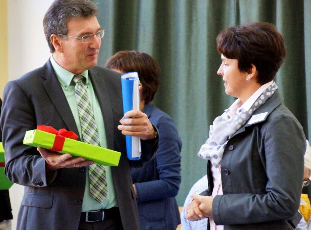 Verbraucherschutzminister Dieter Lauinger überreicht ein Geschenk an die Schulleiterin Frau Trautmann
