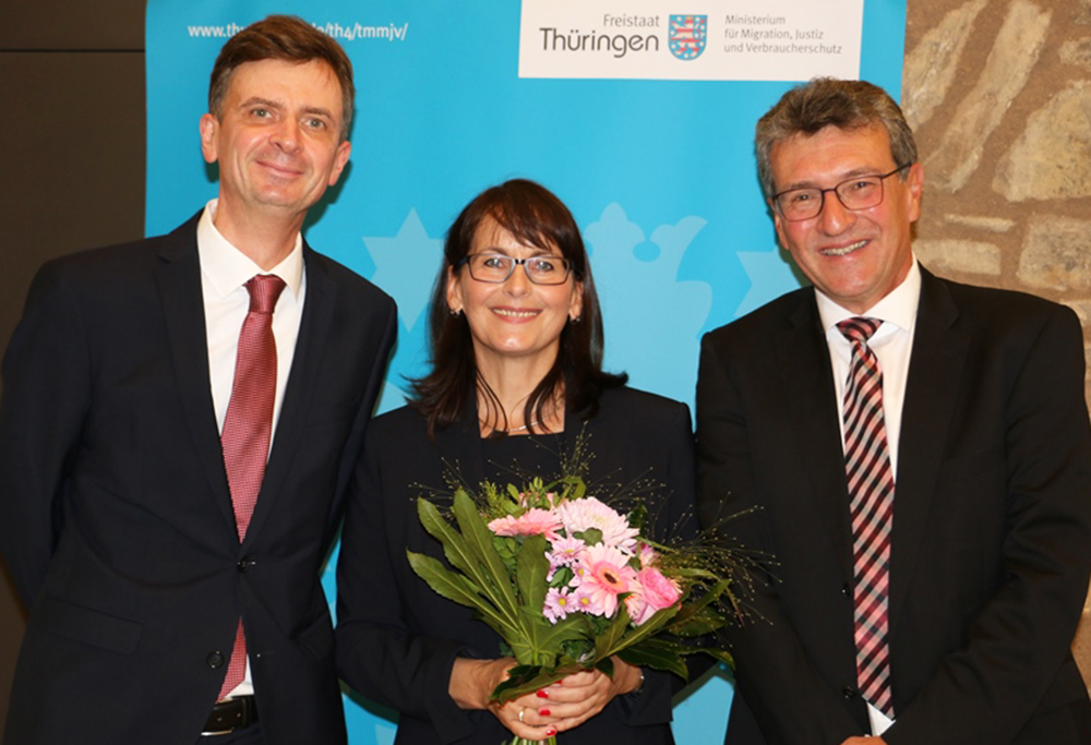 Richterin Engel mit Blumenstrauß halten gesäumt von Minister und Staatssekretär