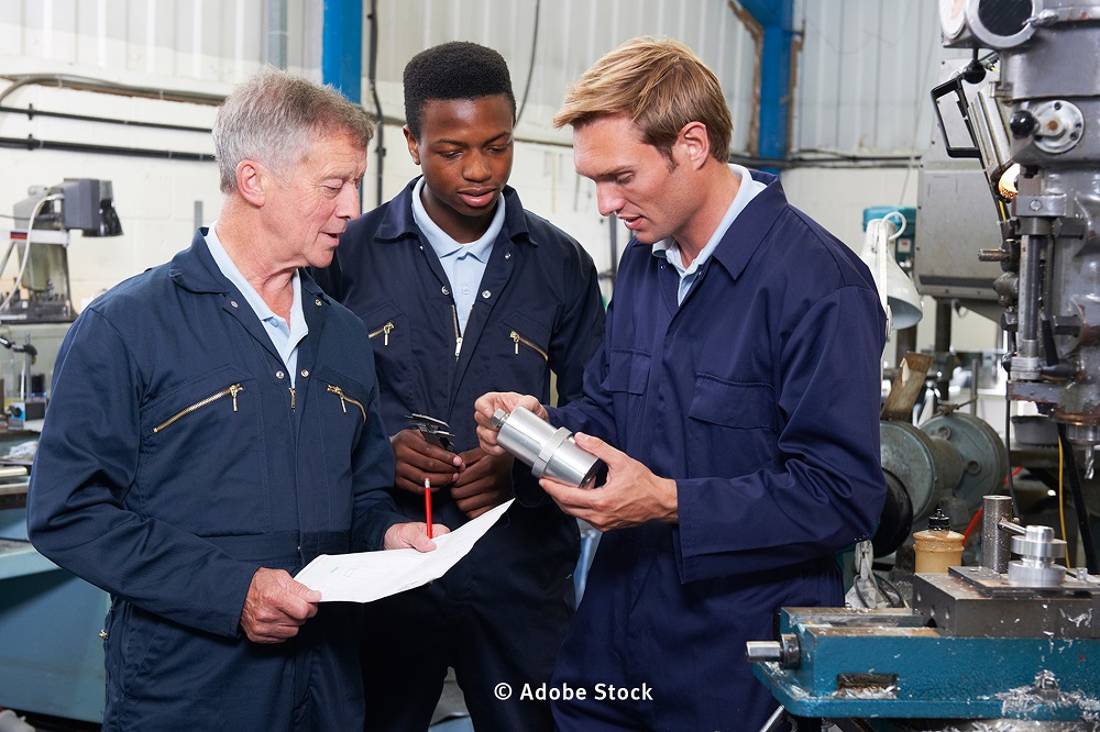 Einem jungen Flüchtling werden bei der Ausbildung in einem Betrieb die Arbeitsschritte erläutert (Foto: Adobe Stock)