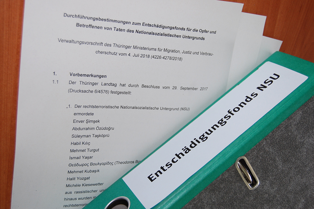 Fonds NSU Blatt Papier mit Informationen zur NSU-Opferentschädigung und ein grüner Ordner mit Aufschrift