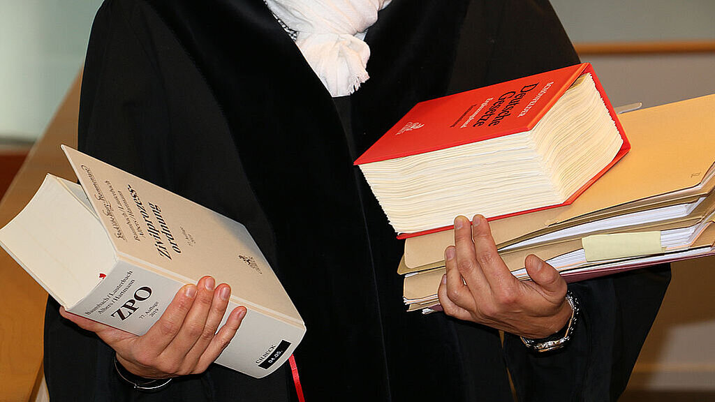 Richteramt Ausschnitt von einer Richterin mit Robe und Gesetzesbüchern und Akten auf dem Arm