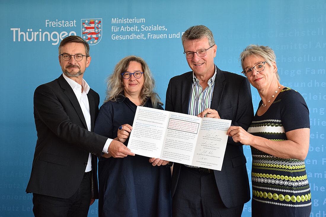 Minister Dieter Lauinger mit drei weiteren Personen den unterzeichneten Schutzbrief in den Händen haltend