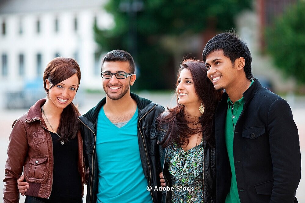 zwei junge Frauen und Männer von verschiedener Nationalität stehen zusammen (Foto: Adobe Stock)