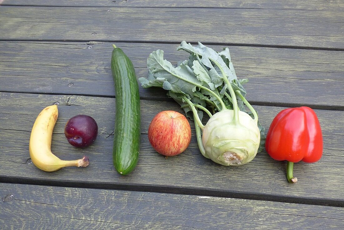 Obst und Gemüse verschiedene Obst und Gemüsesorten liegen auf einen grünen Holztisch