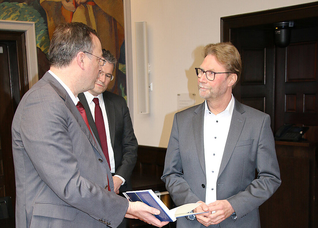 Justizminister Dirk Adams lässt sich das Buch der Forschungsstelle DDR-Recht zeigen.