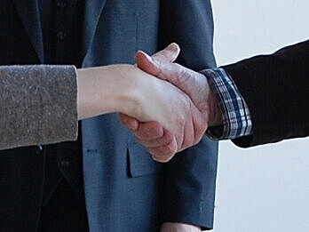 Handschlag zur Einigung in einem Streitschlichtungsverfahren vor einer neutralen beobachtenden Person