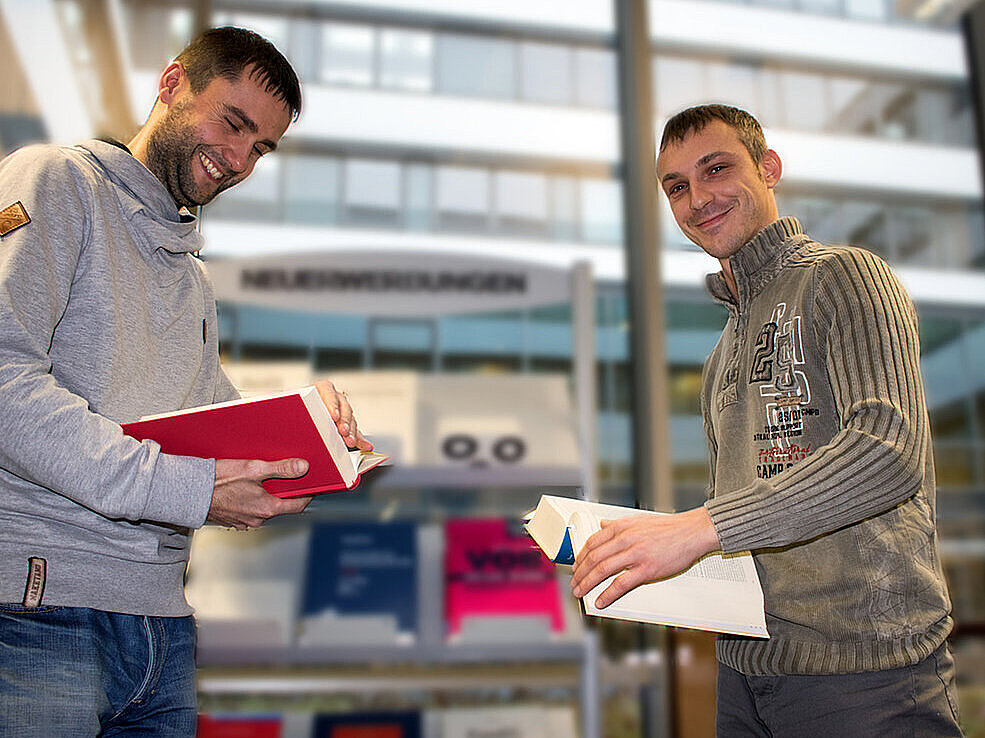 Zwei Justizbeamte blättern in Gesetzesbüchern.