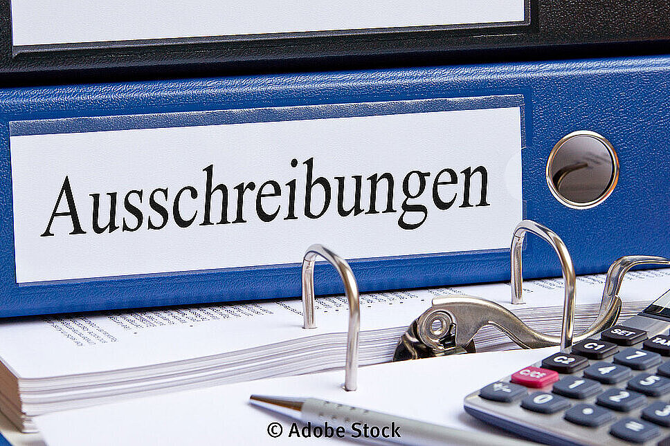 Ordner mit der Aufschrift Ausschreibungen und ein Taschenrechner