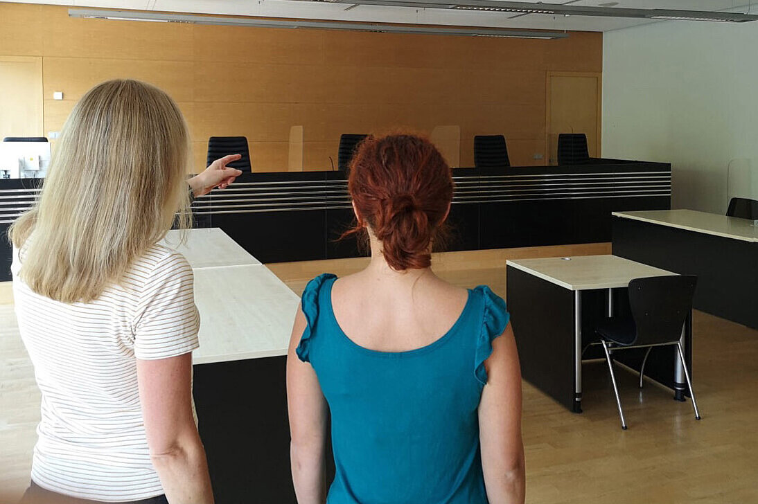 Eine psychosoziale Prozessbegleiterin zeigt einer Geschädigten den Verhandlungssaal..