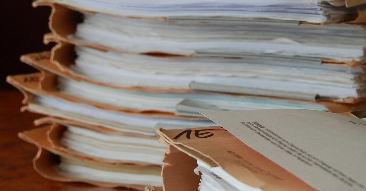 Zwei Stapel Verfahrensakten sind auf dem Schreibtisch des Bearbeiters abgelegt