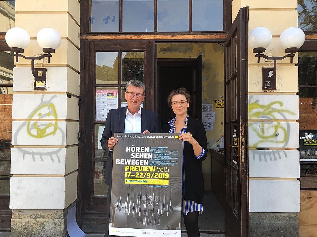 Minister Lauinger hält mit einer weiteren Person ein Werbeschild für eine Veranstaltung im Kulturquartier Erfurt e.V.