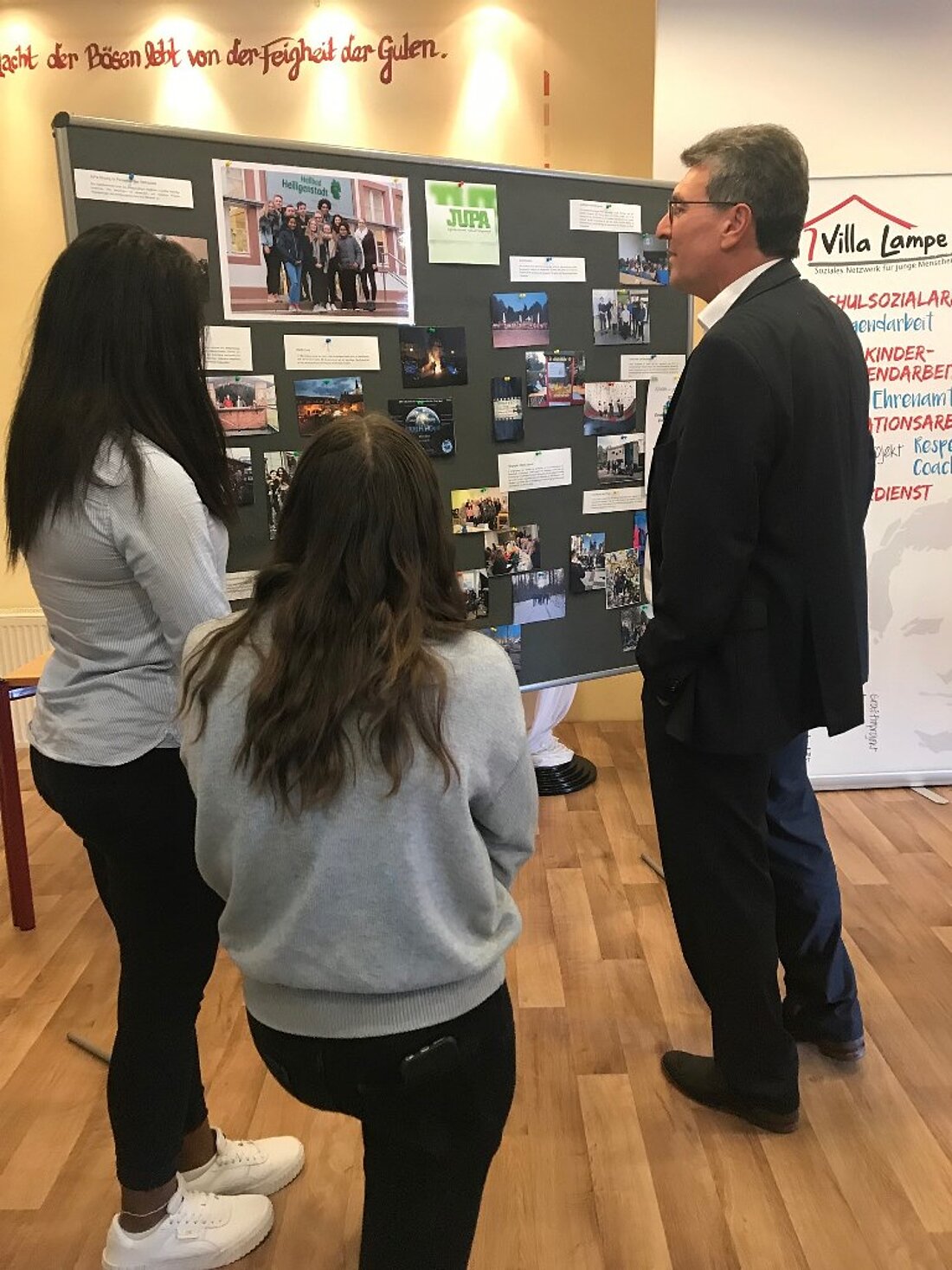 Minister Lauinger mit zwei weiteren Personen eine Schautafel betrachtend