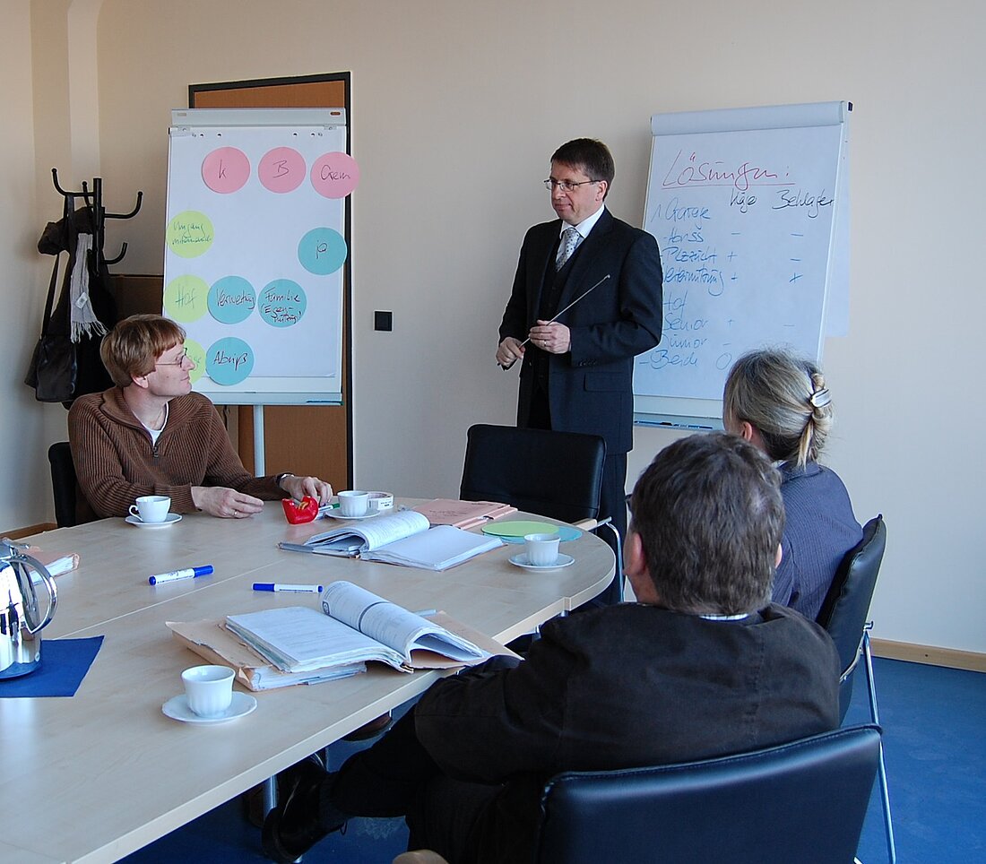 die Parteien sitzen sich in einem Güterichterverfahren an einem runden Tisch gegenüber