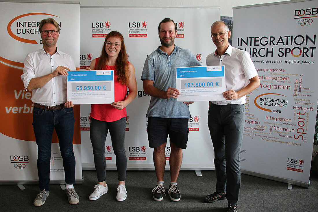 Minister Dirk Adams, die zwei Fachkräfte Michala Michl und Markus Fromm sowie der Hauptgeschäftsführer des Landessportbundes Thüringen bei der Übergabe der Fördermittel. ergibt einen Fördermittelbescheid an den Landes