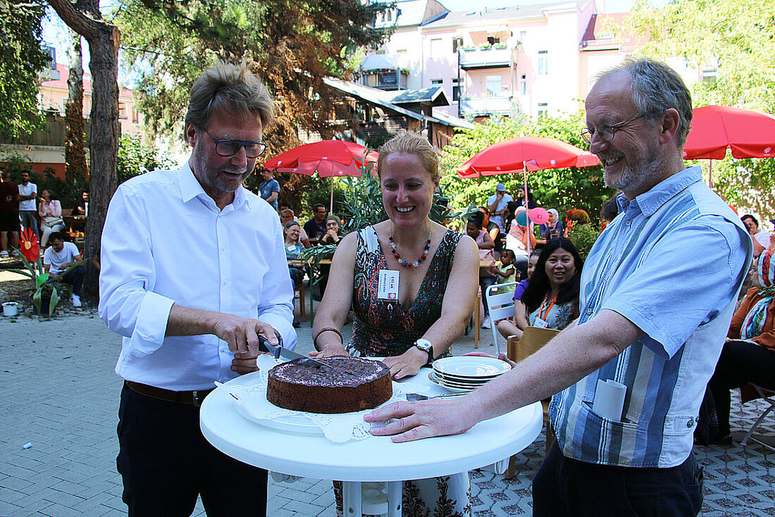 Minister Dirk Adams schneidet bei der Eröffnung des Café Sommergarten International in Weimar ein Stück Torte ab.