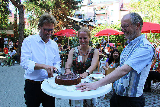 Minister Dirk Adams schneidet bei der Eröffnung des Café Sommergarten International in Weimar ein Stück Torte ab.