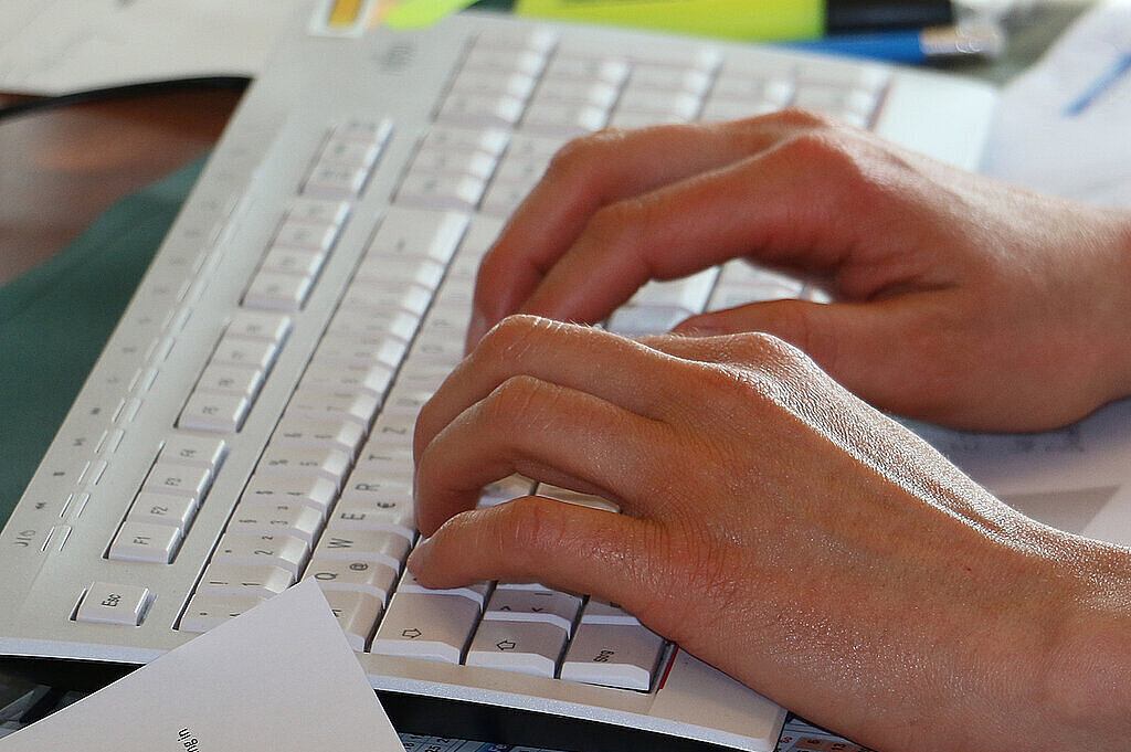 2 Hände schreiben mit der Tastatur einen Text