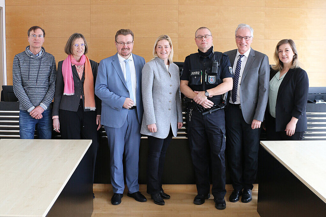 Justizministerin Beate Meißner sowie Staatssekretär Christian Klein und Bedienstete des Thüringer Oberlandesgerichts stehen in einem Sitzungssaal.