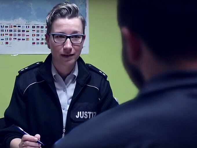 Eine Beamtin des gehobenen Vollzugs- und Verwaltungsdienstes im Gespräch mit einem Gefangenen