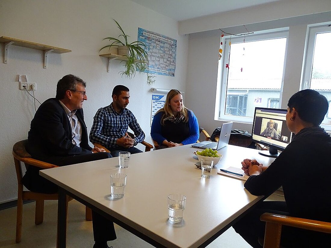 Minister Lauinger verfolgt mit 3 weiteren Personen am Tisch sitzend die Möglichkeit des Videodolmetschens im PC