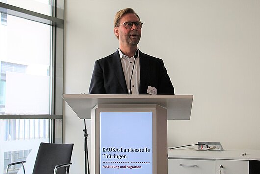 Minister Dirk Adams steht hinterm Rednerpult und hält ein Grußwort bei der Preisverleihung Unternehmen mit Kultur.