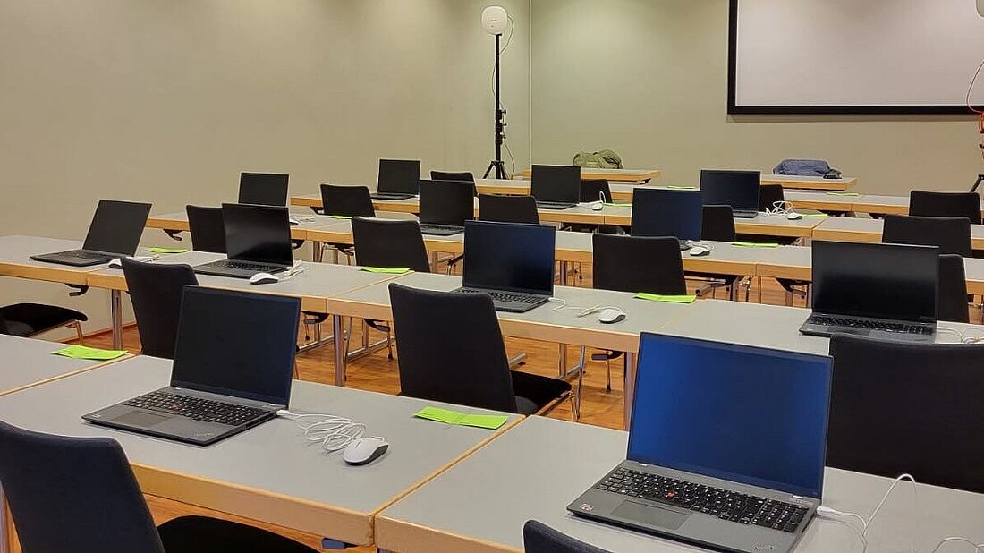 Blick in einen Raum mit Bestuhlung und technischer Ausstattung mit Laptops