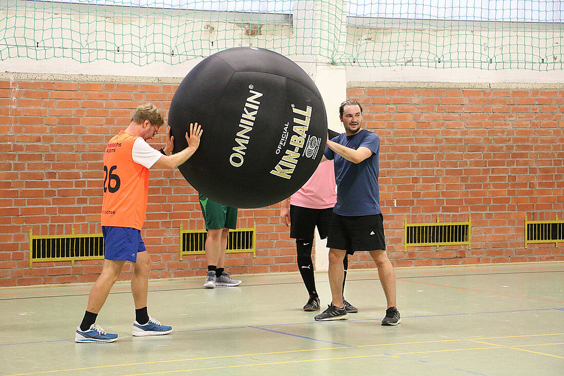 Minister Dirk Adams trainiert gemeinsam mit dem Erfurter Kin-Ball Klub Erfurter Lachse und drückt gegen einen Riesenball, so dass dieser nicht herunterfällt..