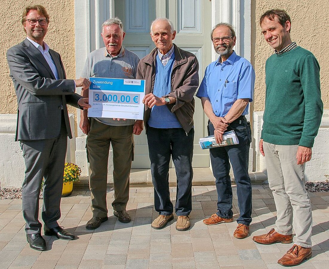 Justizminister Dirk Adams überreicht symbolisch den Lottomittelcheck am Mitglieder der Gemeinde Streufdorf-Eishausen.