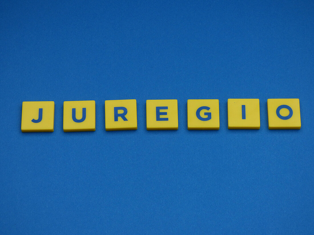 Schriftzug Juregio mit gelben Buchstabensteinen auf blauem Hintergrund gelegt