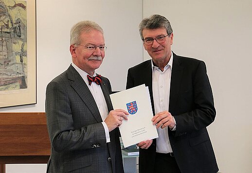 Justizminister Dieter Lauinger überreicht dem Präsidenten des Thüringer Landessozialgerichts Fritz Keller (links) die Ruhestandsurkunde