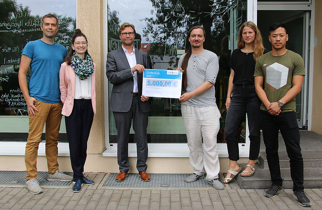 Justizminister Dirk Adams überreicht dem Mitgliedern des Youth Garage e.V. einen Lottomittelbescheid.