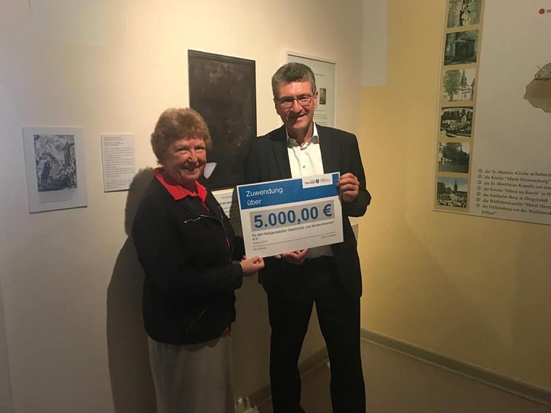 Minister Lauinger und eine weitere Person halten den Lottomittelscheck freudig inden Händen