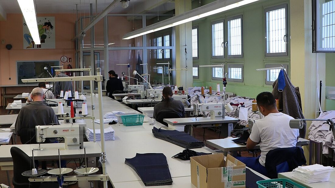 Mehrere Gefangene nähen in einem großen Raum in der Justizvollzugsanstalt Gesichtsmasken. Foto: JVA Hohenleuben