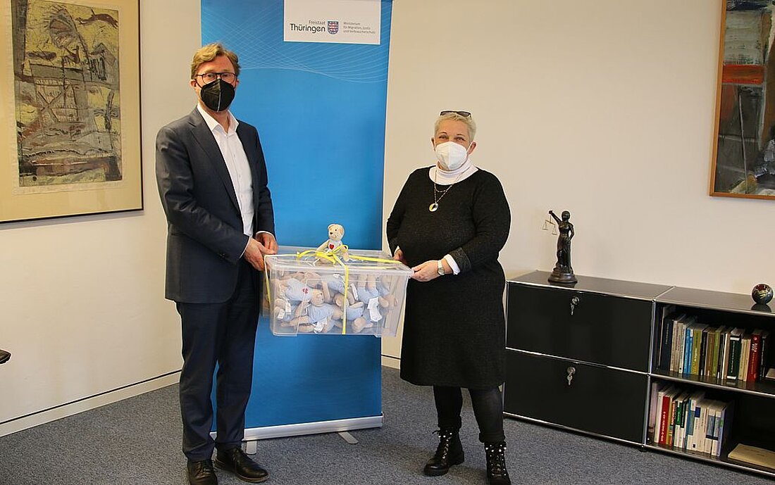 Die Vorsitzende des Hauptpersonalrates, Angelika Schirmer, überreicht Migrationsminister Dirk Adams Spielzeugbären für die vor dem Krieg geflüchteten Kinder aus der Ukraine, welche in der Erstaufnahme erwartet werden.