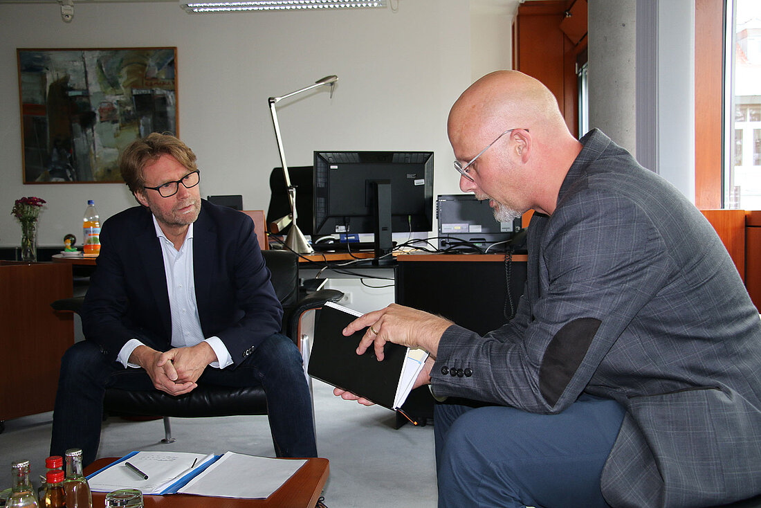 Justizminister Dirk Adams und der Landesbeauftragte für die Aufarbeitung der SED-Diktatur, Dr. Peter Wurschi sitzen im Büro des Ministers und unterhalten sich